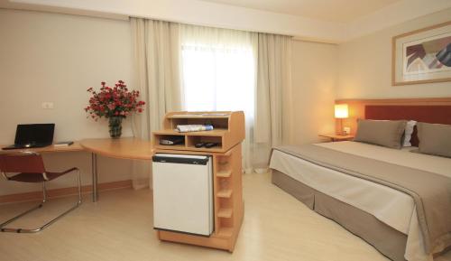 a bedroom with a bed and a desk and a table at Bienal Suítes in Sao Paulo