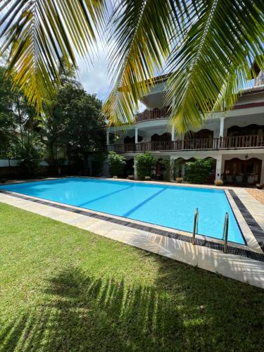 a large blue swimming pool next to a building at Sandali Walauwa in Bentota