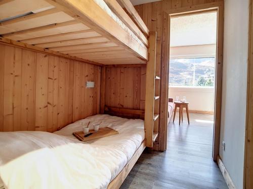 a bed in a room with a wooden wall at Studio rénové confortable, accès piste, balcon sud - FR-1-344-953 in Les Menuires
