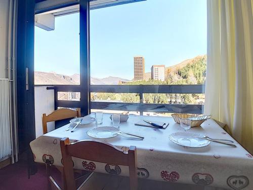 une table blanche avec des chaises et une grande fenêtre dans l'établissement Studio 3 pers, ski aux pieds, balcon nord, TV, cuisine équipée, accès galerie marchande - FR-1-344-966, aux Menuires