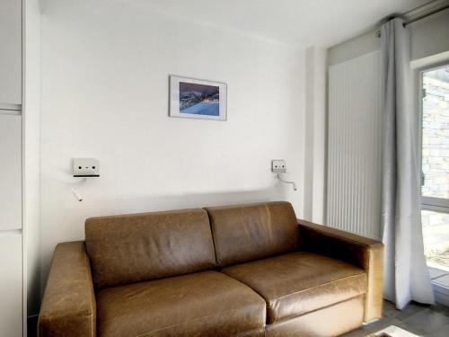 - un canapé brun dans le salon avec une fenêtre dans l'établissement Appartement rénové, 4 pers, proche des pistes, parking gratuit - FR-1-344-958, aux Menuires