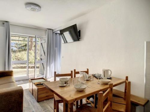 - une salle à manger avec une table en bois et des bols dans l'établissement Appartement rénové, 4 pers, proche des pistes, parking gratuit - FR-1-344-958, aux Menuires