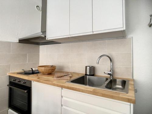 une cuisine avec des armoires blanches et un évier dans l'établissement Appartement rénové, 4 pers, proche des pistes, parking gratuit - FR-1-344-958, aux Menuires