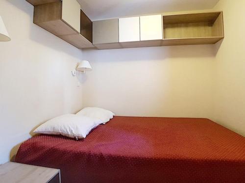 une petite chambre avec un lit avec une couverture rouge dans l'établissement Appartement standard Départ ski aux pieds Balcon - FR-1-344-988, aux Bruyères