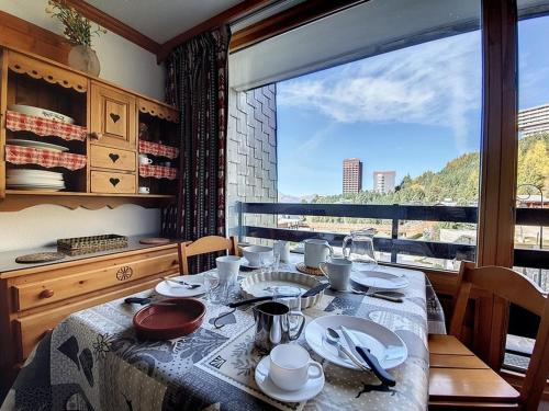 une salle à manger avec une table et une grande fenêtre dans l'établissement Studio agréable Au pieds des pistes Balcon nord - FR-1-344-995, aux Menuires