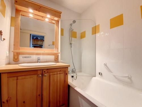 une salle de bain avec un lavabo, une baignoire et un miroir dans l'établissement Studio agréable Au pieds des pistes Balcon nord - FR-1-344-995, aux Menuires