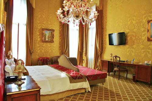 a bedroom with a large bed and a chandelier at Pesaro Palace in Venice