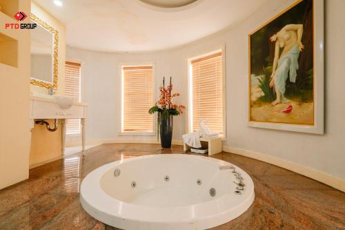 a large white bath tub in a room with a painting at White Hotel in Ha Tinh
