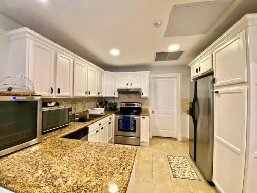 a kitchen with white cabinets and stainless steel appliances at Stylish Lux Beach Condo Aquamarina Cap Cana in Punta Cana