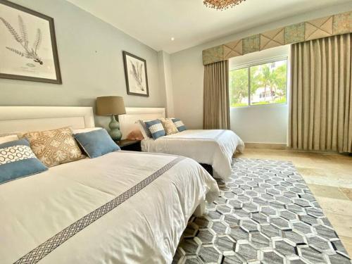 a bedroom with two beds and a window at Stylish Lux Beach Condo Aquamarina Cap Cana in Punta Cana