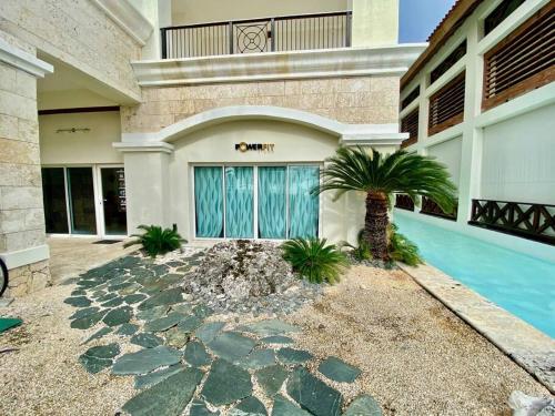 a house with a palm tree in front of a swimming pool at Stylish Lux Beach Condo Aquamarina Cap Cana in Punta Cana