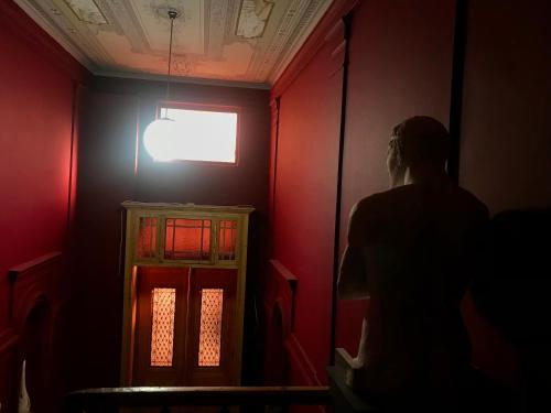 a person walking through a red room with a window at VASILIKON Hotel 1888 the past is present HISTORICAL PRESERVATION MONUMENT in Kalamata