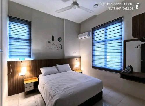 a bedroom with a large bed and two windows at GUESTHOUSE #2 Semi Bungalow House in Kuah