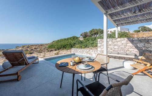 a patio with a table and chairs and the ocean at Ariadne Suites in Mytakas