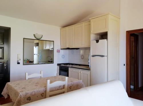 a kitchen with a table and a white refrigerator at B&B La Torre Elite in Santa Teresa Gallura