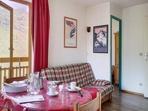 une pièce avec une table et une chaise avec un rideau rouge dans l'établissement Appartement cosy au pied des pistes avec balcon – 5 personnes, 32 m² - FR-1-344-1026, aux Menuires
