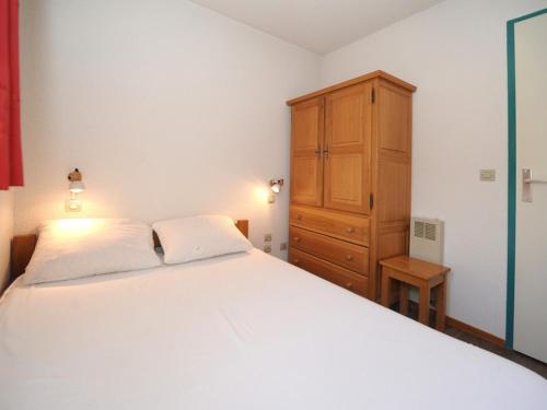 une chambre avec un lit blanc et une armoire en bois dans l'établissement Appartement cosy au pied des pistes avec balcon – 5 personnes, 32 m² - FR-1-344-1026, aux Menuires