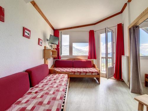- un salon avec un canapé et des rideaux rouges dans l'établissement Studio lumineux Proche des pistes Balcon - FR-1-344-1035, aux Menuires