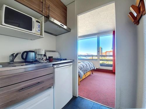 une cuisine avec un four micro-ondes et une chambre avec un lit dans l'établissement Appartement cosy, 4 pers, balcons, aux pieds des pistes - FR-1-344-1044, aux Menuires