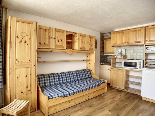 une cuisine avec des armoires en bois et un canapé dans une pièce dans l'établissement Studio lumineux Centre station Balcon - FR-1-344-1046, aux Menuires