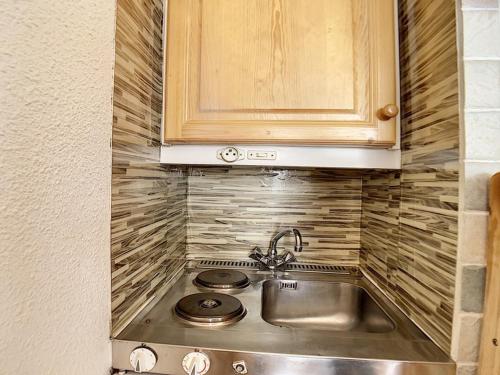 une cuisine avec un évier et des armoires en bois dans l'établissement Studio lumineux Centre station Balcon - FR-1-344-1046, aux Menuires