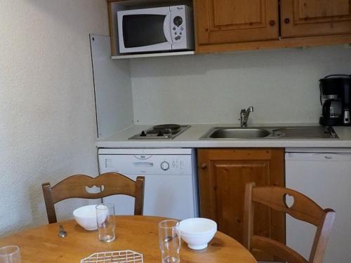 une cuisine avec une table en bois et un micro-ondes dans l'établissement Appartement cozy 2 pièces · Proche pistes et commerces · Balcon sud/est · 4 pers - FR-1-344-1023, aux Menuires