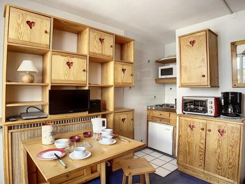 une cuisine avec des armoires en bois et une table en bois dans l'établissement Studio cosy pour 2 au cœur de La Croisette, accès pistes à 150m - FR-1-344-1029, aux Menuires