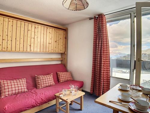 un salon avec un canapé rouge et une table dans l'établissement Studio cosy pour 2 au cœur de La Croisette, accès pistes à 150m - FR-1-344-1029, aux Menuires