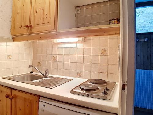 une cuisine avec une cuisinière et un évier dans l'établissement Appartement skis aux pieds avec balcon et 2 chambres - FR-1-344-1037, aux Menuires
