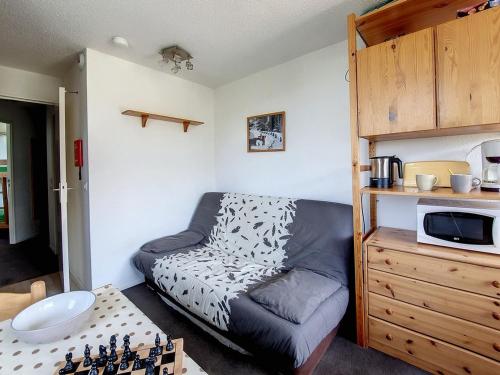 Cette petite chambre comprend un lit et un four micro-ondes. dans l'établissement Studio confortable proche des pistes avec balcon et cuisine équipée - FR-1-344-1043, aux Menuires