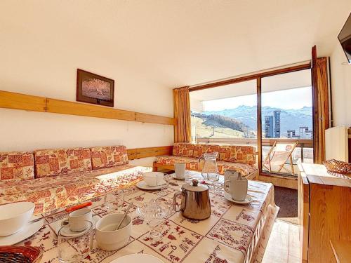un salon avec une table et une grande fenêtre dans l'établissement Appartement lumineux au cœur de la station avec balcon sud, accès direct aux pistes, 5 pers. - FR-1-344-1059, aux Menuires