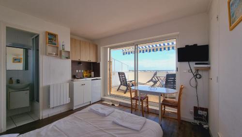 a room with a bed and a kitchen with a balcony at Appartements front de mer Royan in Royan