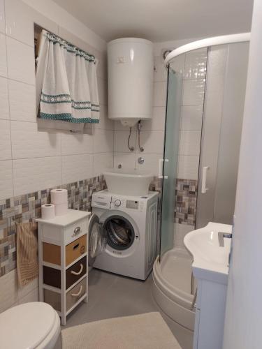 a bathroom with a washing machine and a sink at Premantura Studio apartman in Premantura