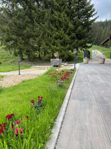 a park with a bench and flowers in the grass at Chalet Schwendli in Schwarzsee