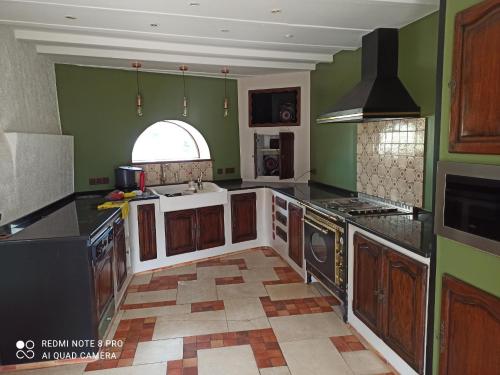 a kitchen with green walls and wooden cabinets at G1 les oliviers in Saint-Germain-de-Prinçay