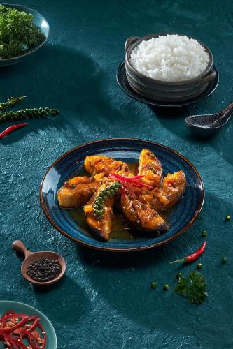 a blue plate with chicken and rice on a table at Canary Dalat Hotel in Da Lat