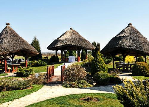 two gazebos with thatched roofs in a park at S Club Resort Hotel Aqua Park and Spa in Belgrade
