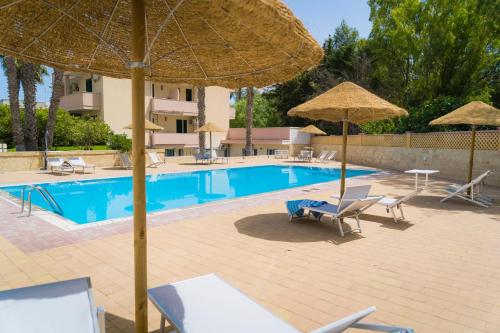 una piscina con sombrillas y tumbonas y una piscina en Vaia Residence, en Torre dell'Orso