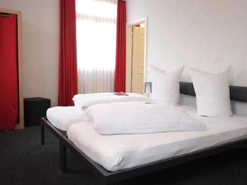 1 dormitorio con 2 camas con sábanas blancas y ventana en Hotel Brauerei Frohsinn, en Arbon