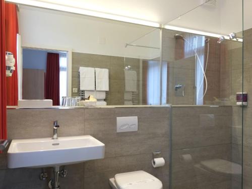 uma casa de banho com um lavatório, um WC e um espelho. em Hotel Brauerei Frohsinn em Arbon