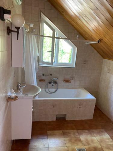 ein Bad mit einer Badewanne, einem Waschbecken und einem Fenster in der Unterkunft PBJ Apartman in Pilisborosjenő
