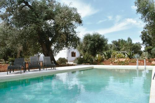 a swimming pool with two chairs and a swimming pool at Trulli Monte Madre in San Vito dei Normanni