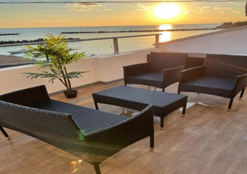un patio all'ultimo piano con sedie, tavoli e l'oceano di Small Resort Shima - Vacation STAY 96429v a Shima