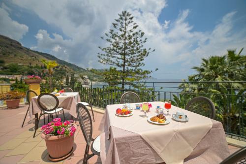 a table with plates of food on a balcony at Hotel Baia Delle Sirene in Taormina