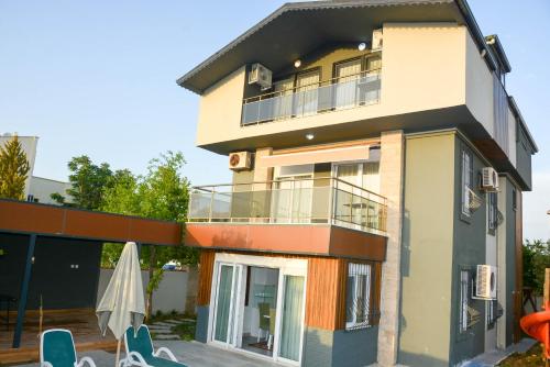 a building with chairs and an umbrella in front of it at BEGONVİL VİLLA in Belek