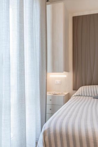 a bedroom with a bed and a window with curtains at Hotel Loretta & Dependance in Cervia