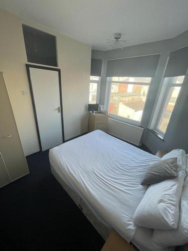 a bedroom with a large white bed with two windows at Northern Pearl Hotel in Blackpool