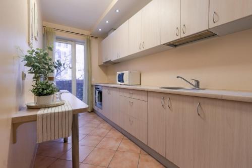 a kitchen with white cabinets and a table with a plant at Mara in Vilnius