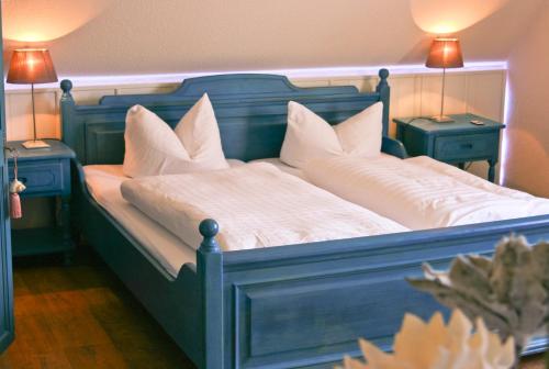 a blue bed with white pillows and two night stands at Landhaus Krabbe von Greetsiel in Greetsiel