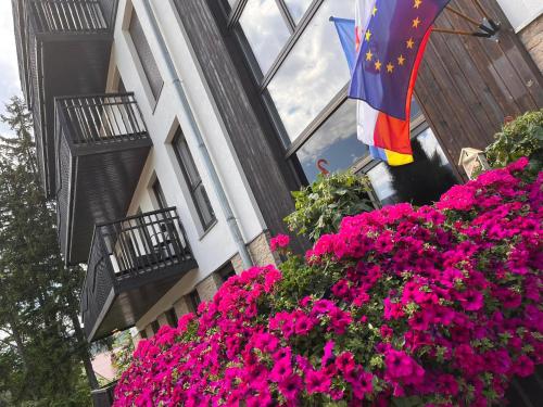 a flag and flowers in front of a building at Apartamentowiec Panorama Gór City Center Family&Pet-friendly in Szklarska Poręba